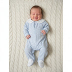 Newborn wearing baby blue footsteps sleepsuit from the 6-piece gift set